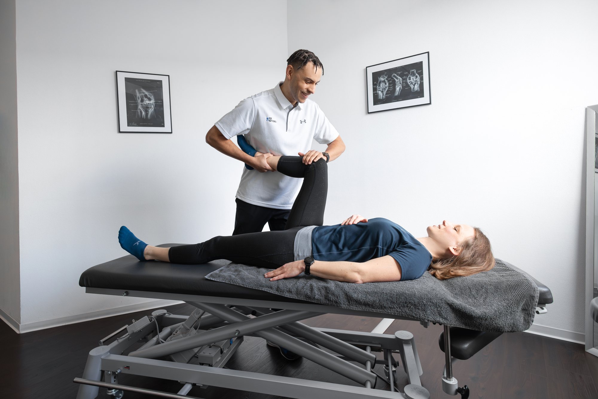 Oliver, Der Hüftcoach, testet bei einer Klientin auf der Liege die Beweglichkeit der Hüfte